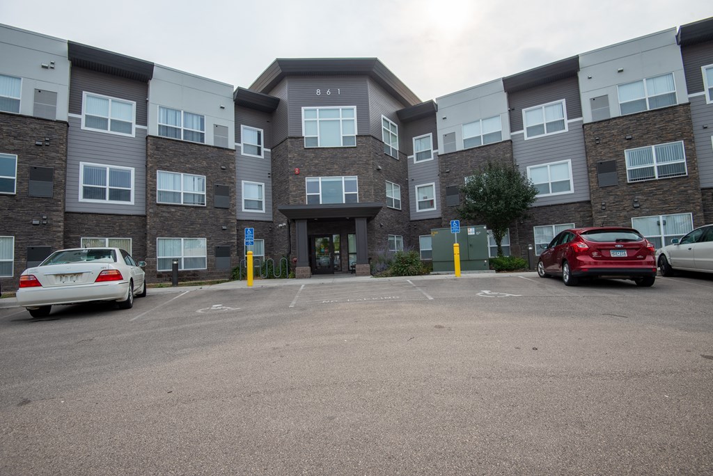 A parking lot in front of a multi-story apartment building.