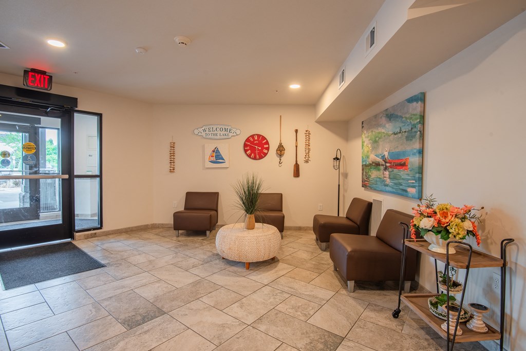 A lobby area with a chair, a table, and a painting on the wall.
