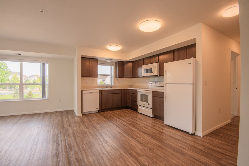 A kitchen with white appliances and wooden floors.