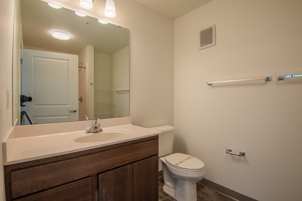 A bathroom with a toilet, sink, and mirror.
