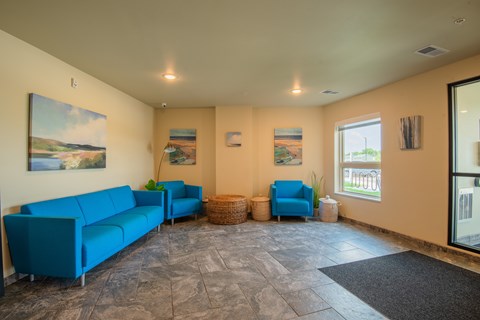 A living room with blue couches and pictures on the wall.