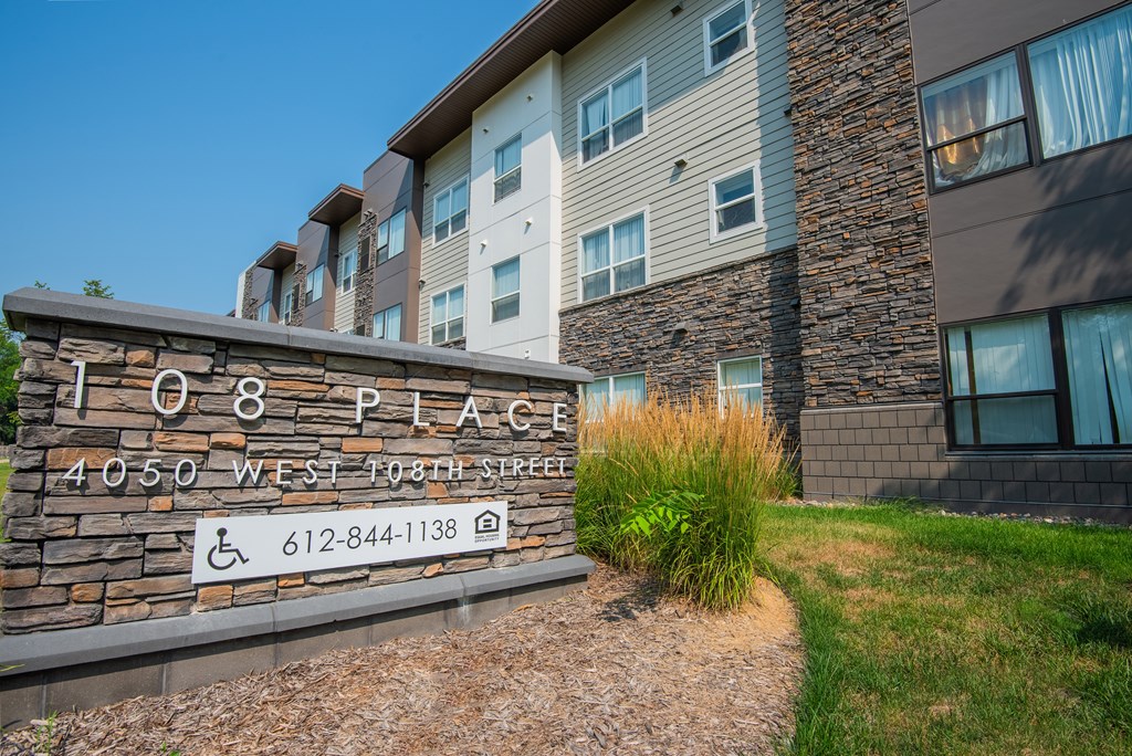 The image shows a building with the number 108 on a stone sign in front of it.