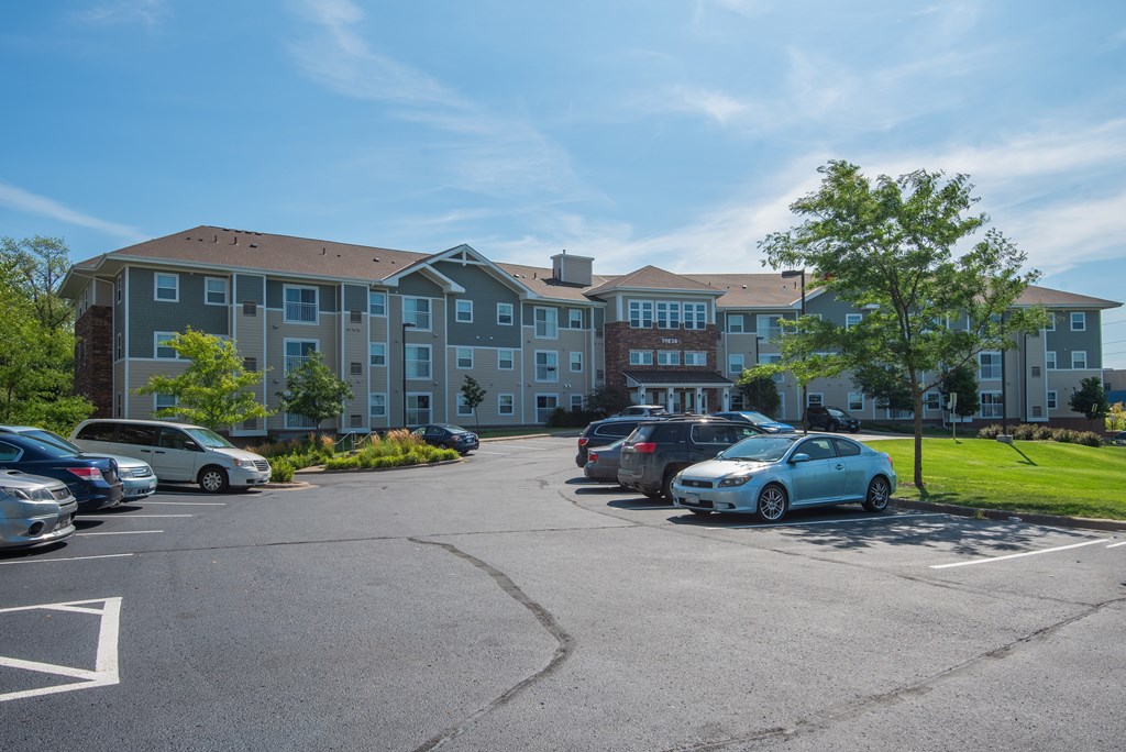A parking lot in front of a large apartment building.