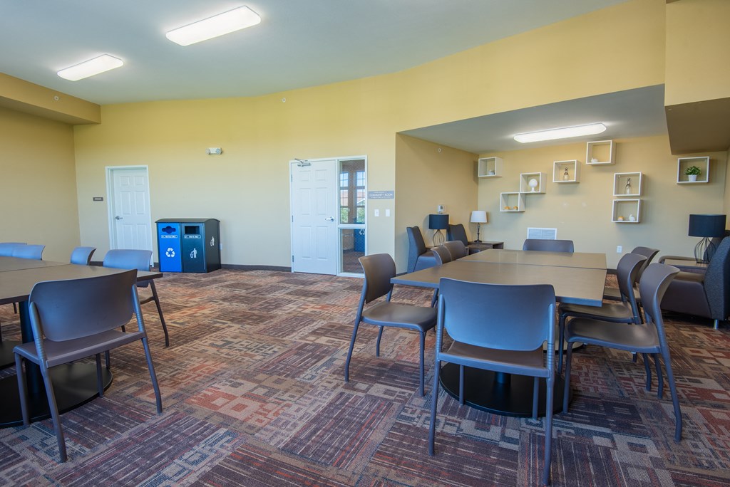 A room with tables and chairs and a vending machine.