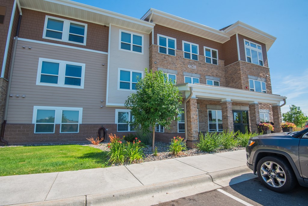 A modern two-story apartment building with a car parked in front.