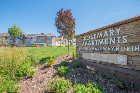A sign for Rosemary Apartments is in front of a grassy area.