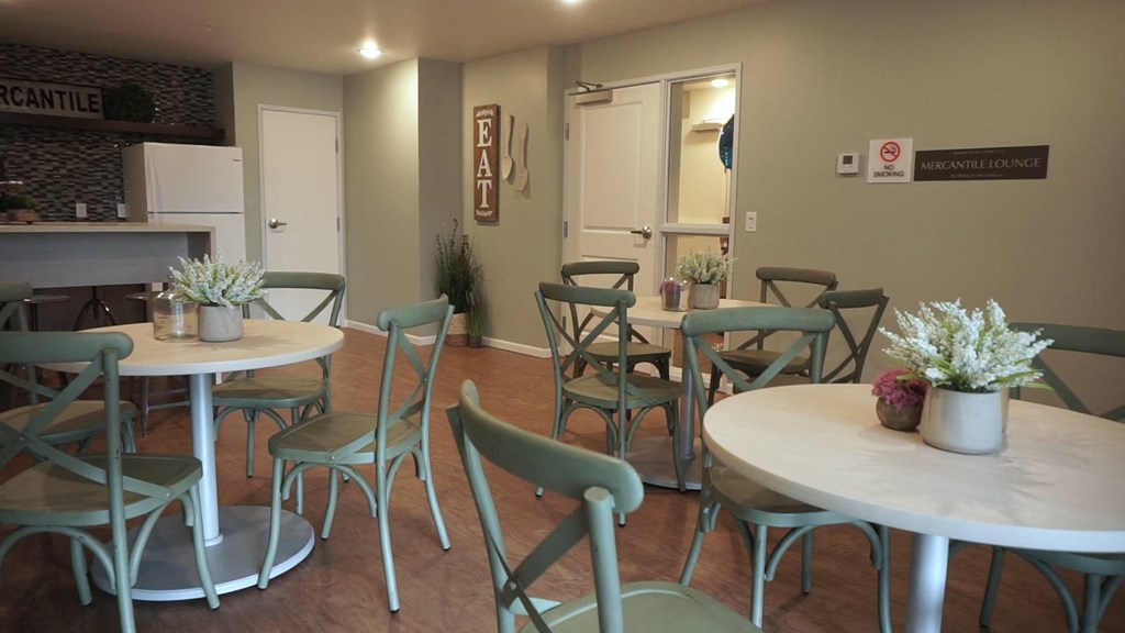 a dining room with tables and chairs and a kitchen