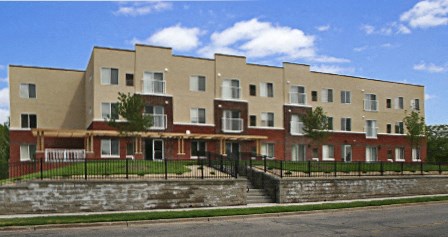 A large brick building with a black fence in front.