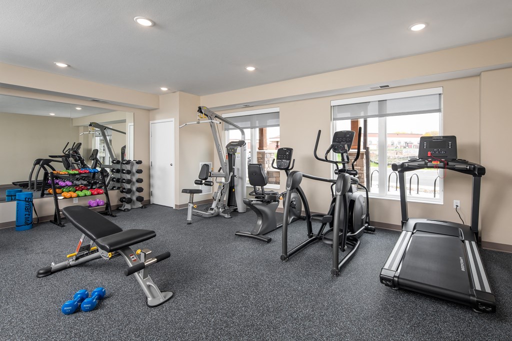 a gym with treadmills and other exercise equipment in a room with windows