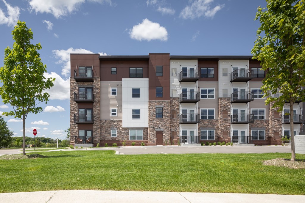 an apartment building with brick and stone exterior and green grass