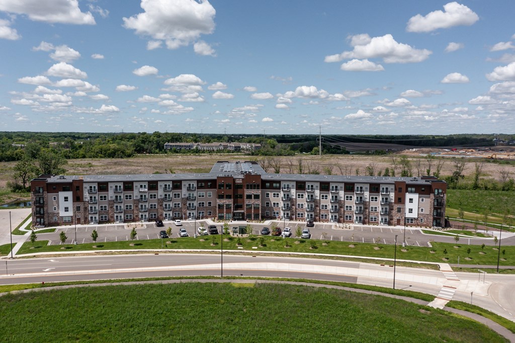 an aerial view of an apartment building overlooking a road and a field