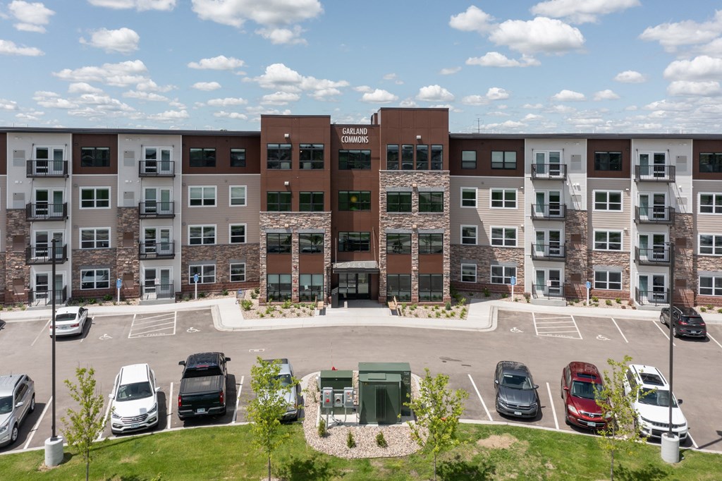 an aerial view of an apartment building with parking lot and cars
