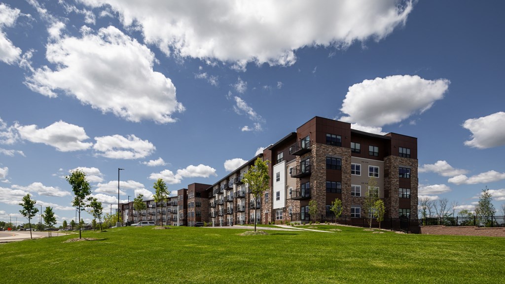 an apartment building on a hill with a grass field