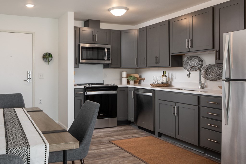 a kitchen with black cabinets and stainless steel appliances and a dining room table