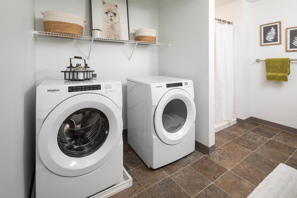 a washer and dryer in a laundry room with a shower and a shelf