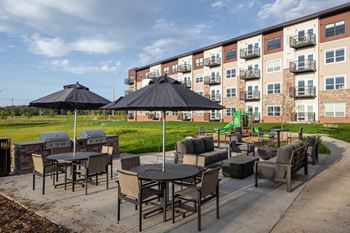 a patio with tables and umbrellas in front of an apartment building