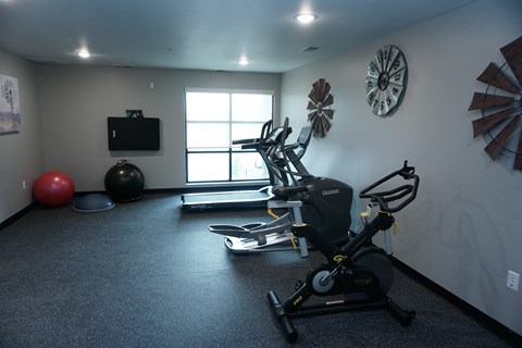 a gym with exercise equipment in a room with a window