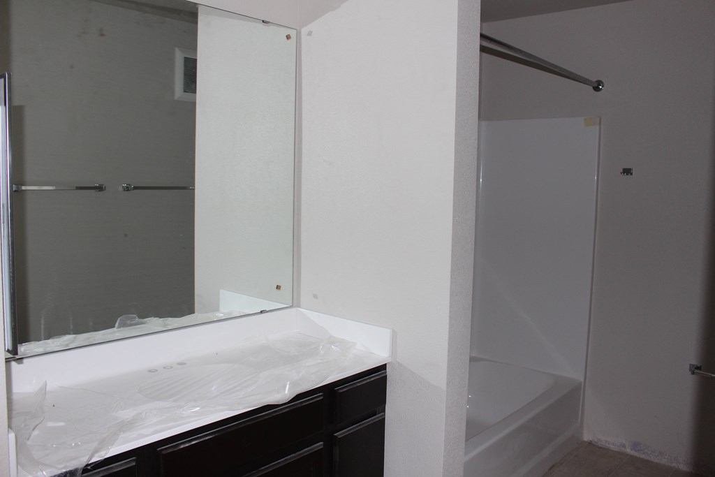 A bathroom with a sink, mirror, and shower.