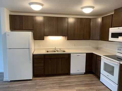 A kitchen with white appliances and brown cabinets.