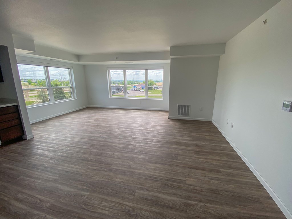 A room with wooden flooring and a window overlooking a parking lot.