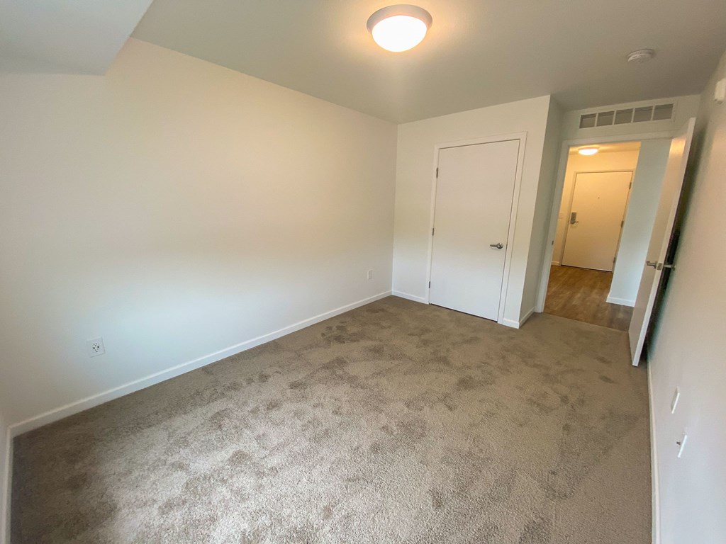 A carpeted room with a door and a light on the ceiling.