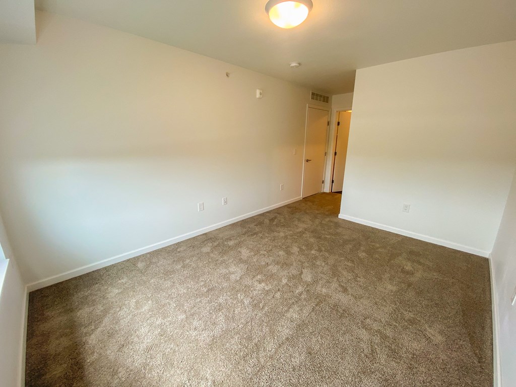A carpeted room with a doorway leading to another room.