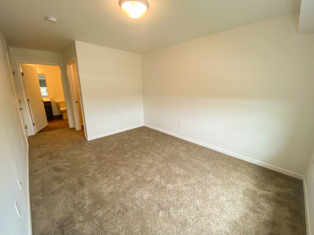 A room with a carpeted floor and a doorway leading to another room.