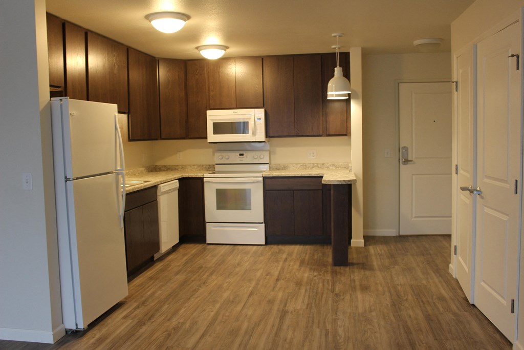 A kitchen with white appliances and brown cabinets.