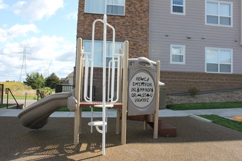 A playground with a slide and a sign with letters on it.