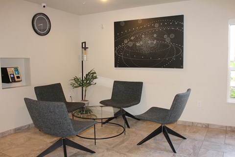 A living room with a large black and white painting of a galaxy on the wall and four grey chairs.