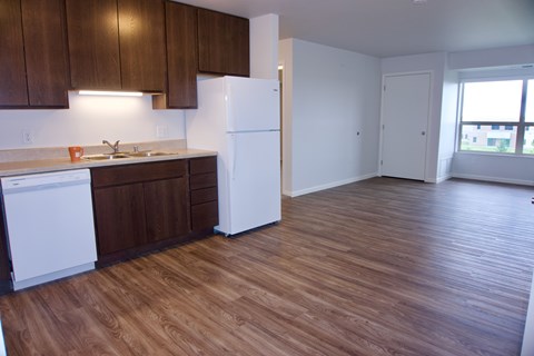 an empty kitchen with white appliances and wood flooring in an apartment