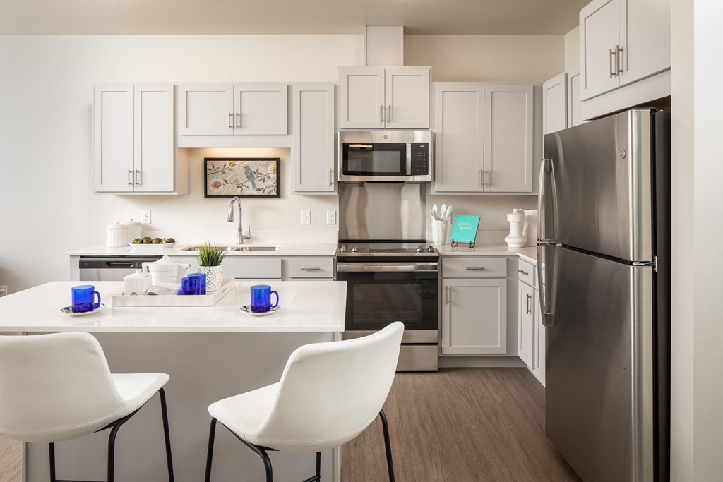 a kitchen with stainless steel appliances and a table with white chairs