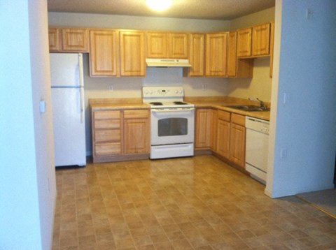 A kitchen with wooden cabinets and white appliances.