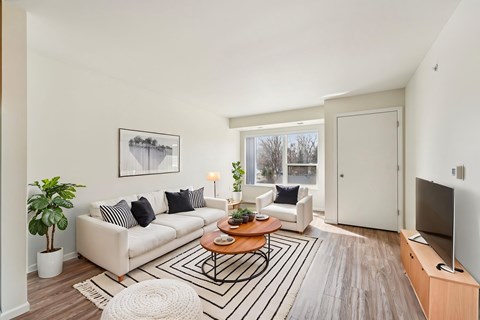 A living room with a white couch, a coffee table, and a television.