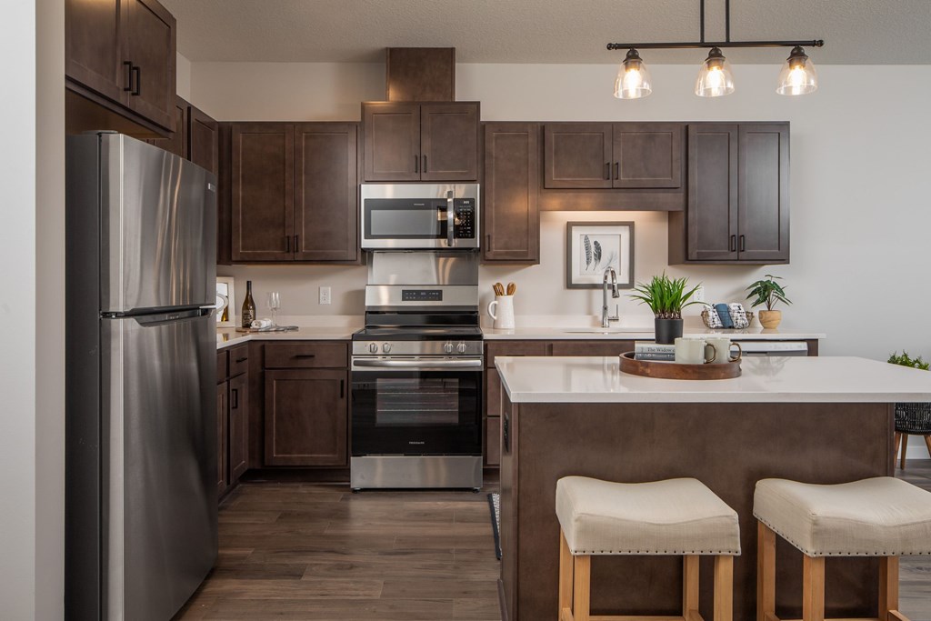 A modern kitchen with a refrigerator, oven, and bar stools.