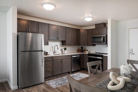 a kitchen and dining room with stainless steel appliances and dark wood cabinets