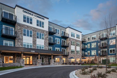 The image shows the exterior of Oakdale Commons apartment building at dusk.