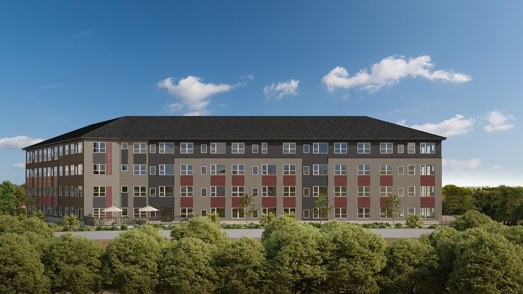 A large building with a flat roof and a lot of windows is surrounded by trees.