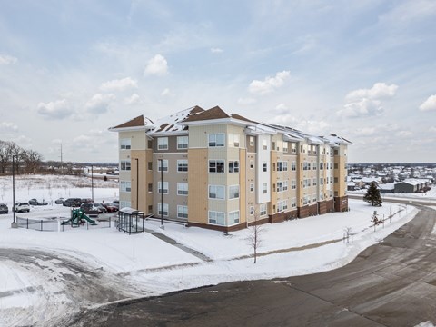 A large apartment complex with a playground in the snow.