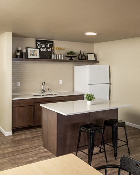 A kitchen with a white fridge and brown bar stools.