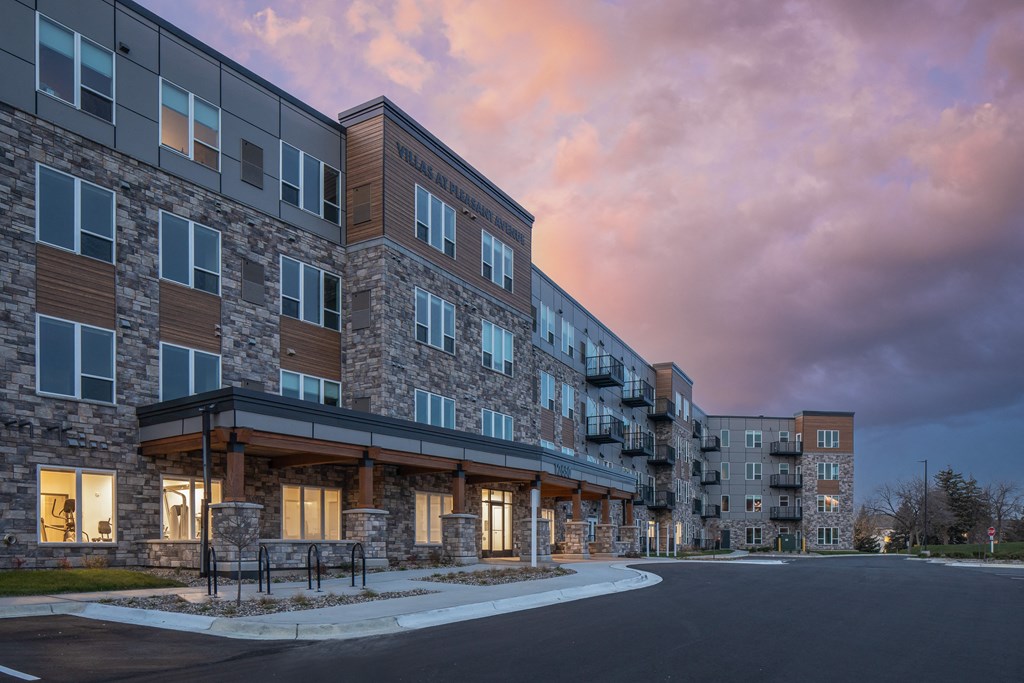 a large apartment building with a sunset in the background