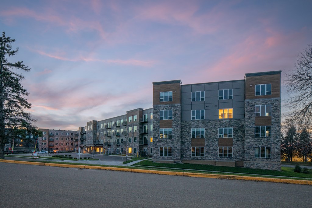 an apartment building on a street corner at dusk