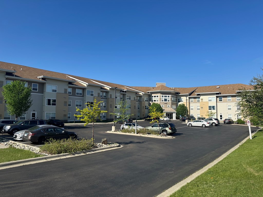 A sunny day at a residential complex with cars parked in the lot.