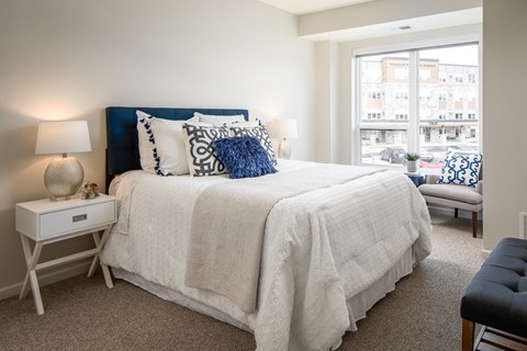 A bedroom with a large bed and a window overlooking a street.