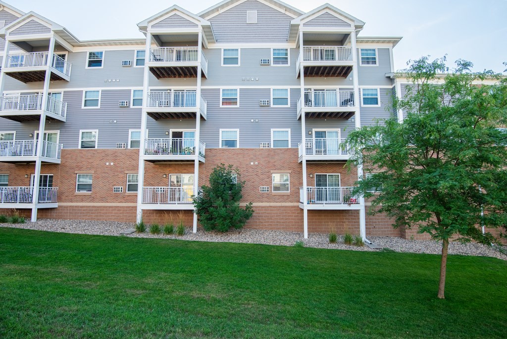 an exterior view of an apartment building with grass and trees