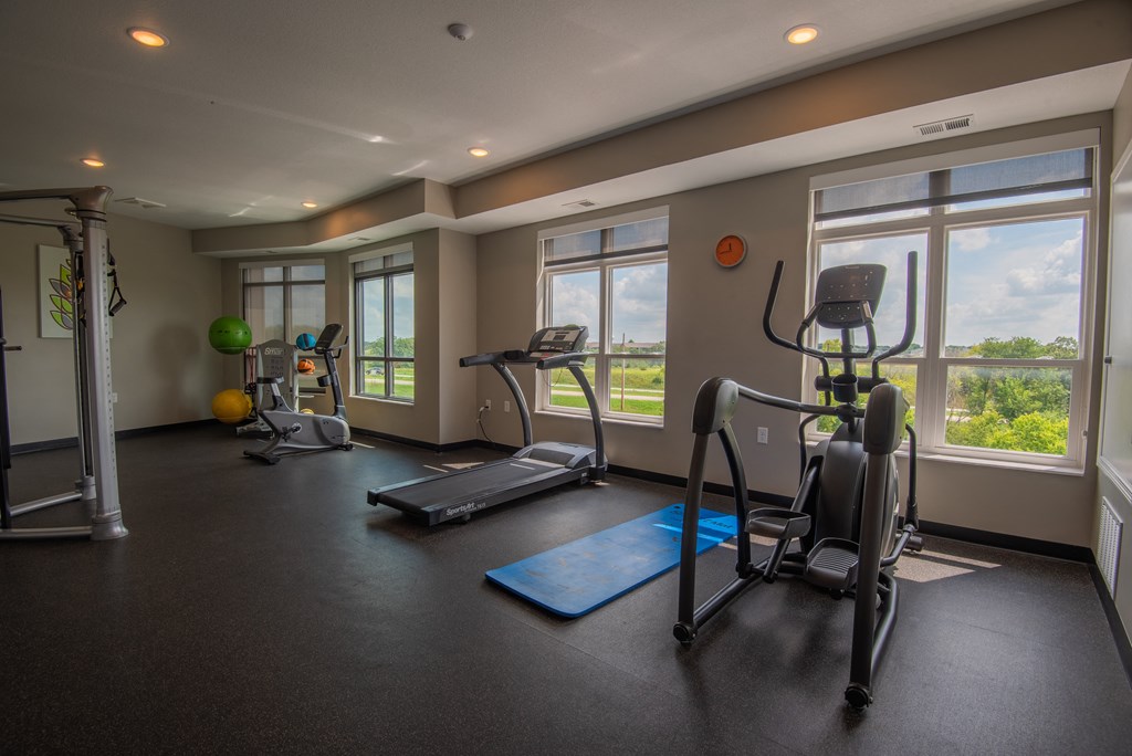 a gym with exercise equipment on the floor and windows