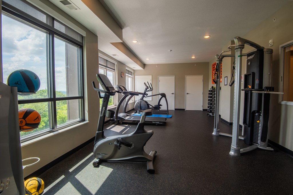 a gym with treadmills and other exercise equipment in a building with large windows