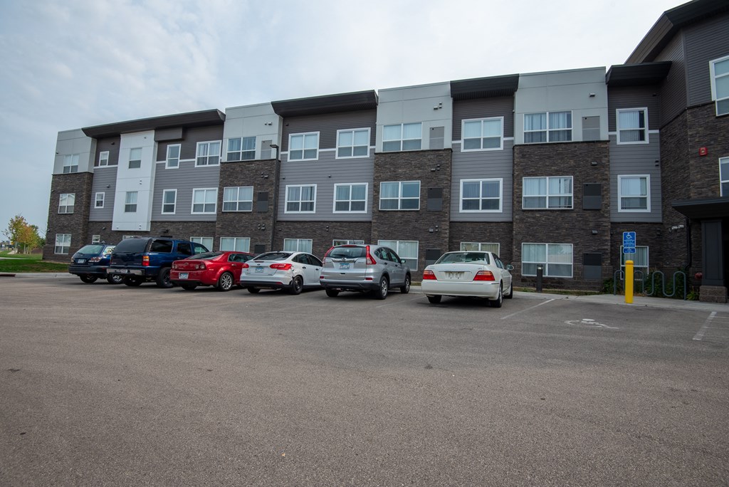 a parking lot with cars in front of an apartment building