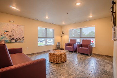 A living room with a large painting, two chairs, and a wicker ottoman.