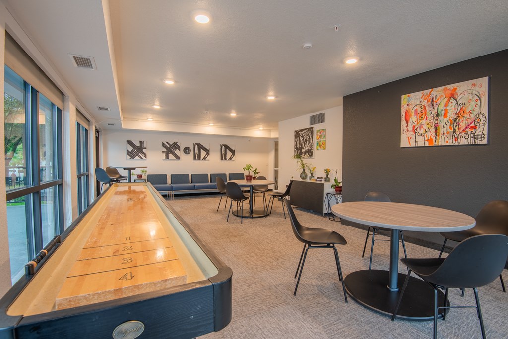 A room with a pool table and chairs.